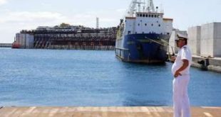 Oficial da Guarda Costeira italiana fala em seu rádio enquanto o navio chega ao porto de Génova, no norte da Itália