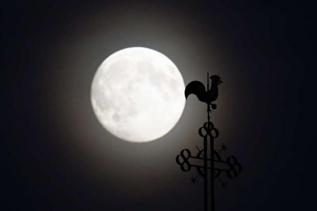 O cata-vento da igreja de São Pedro e São Paulo é retratado na frente da lua na vila de Klein-Auheim perto de Hanau, na Alemanha (Foto: Reuters)