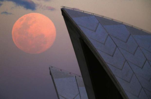 A Superlua sobe por trás do teto do Sydney Opera House neste domingo (horário local). O evento astronômico ocorre quando a lua está mais próxima da Terra em sua órbita, fazendo com que pareça muito maior e mais brilhante do que o habitual (Foto: Reuters)