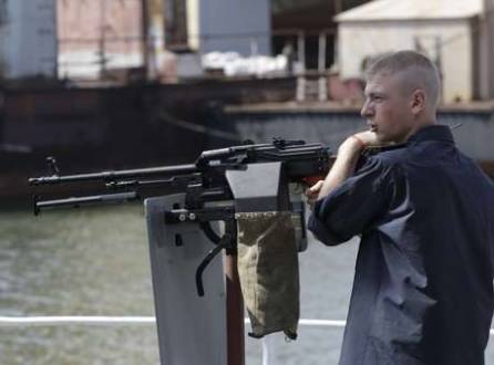 Soldado ucraniano fica ao lado de arma no porto de Mariupol