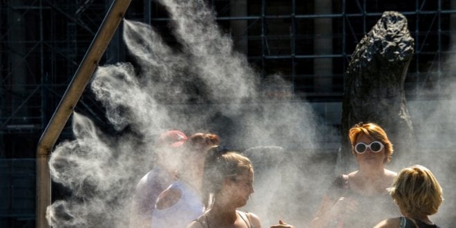 Mulheres se refrescam com borrifador de água público em Lille, na França, durante onda de calor no verão deste ano — Foto: Philippe Huguen/AFP