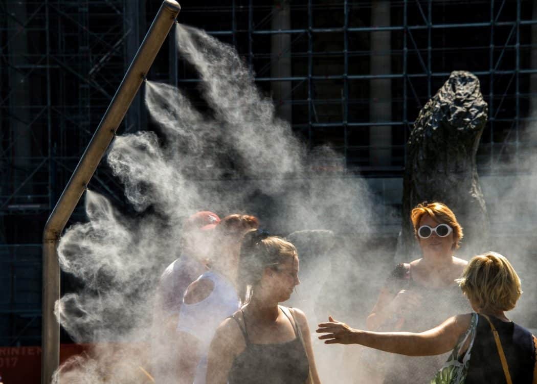 Mulheres se refrescam com borrifador de água público em Lille, na França, durante onda de calor no verão deste ano — Foto: Philippe Huguen/AFP