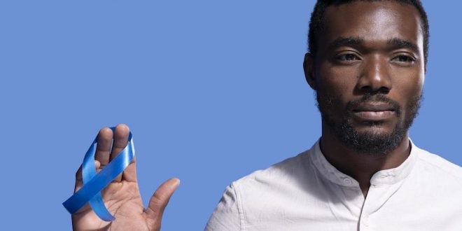 Homem segura fita azul em referência a prevenção de doenças masculinas
