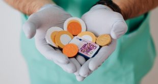 Médico com moedas e dinheiro nas mãos