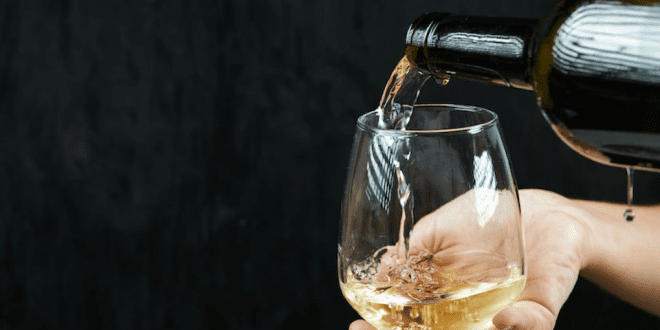 Mão coloca vinho na taça