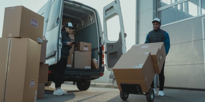 Entregadores colocam caixas dentro de van