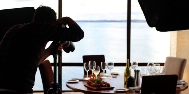 Pessoa tira foto de prato de comida que está sobre a mesa