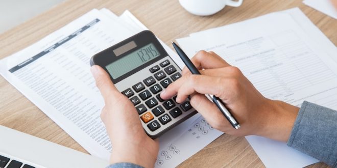 Mão de homem faz conta na calculadora