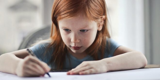 Menininha escrevendo no papel