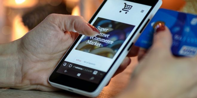Pessoa segura cartão em uma mão e na outra um celular num site de compras