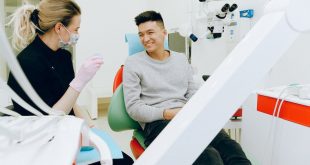 Homem sorri em cadeira de dentista