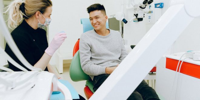 Homem sorri em cadeira de dentista