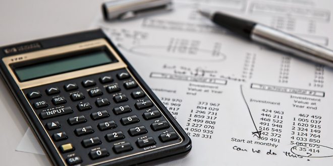 Calculadora ao lado de papel com anotações e caneta