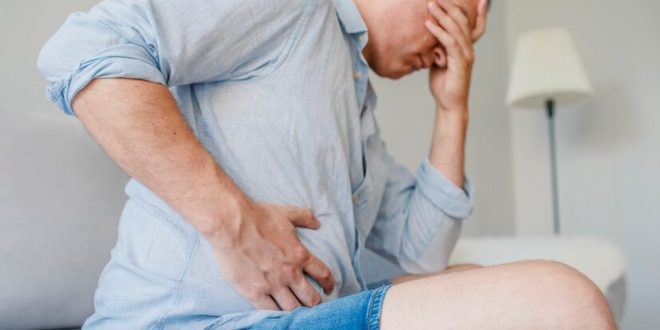 Homem com mão na barriga demonstrando dor