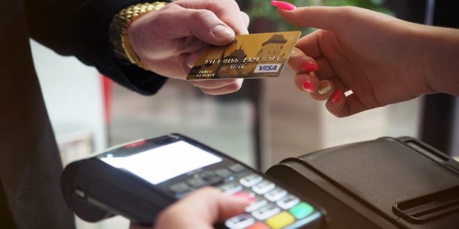 Pessoa entrega cartão para vendedora passar na máquina