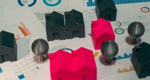Uma mesa com contrato imobiliário, miniatura de casa