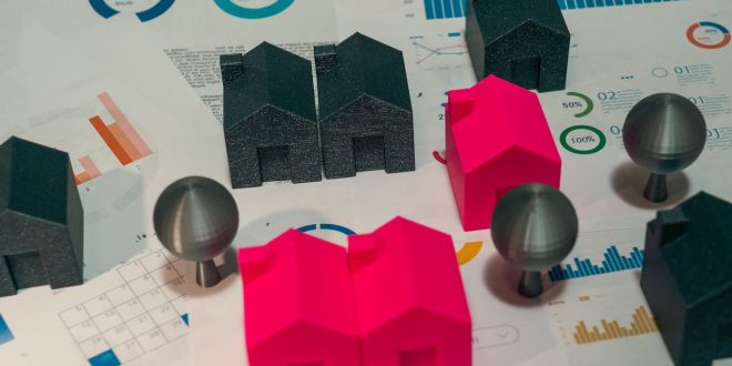 Uma mesa com contrato imobiliário, miniatura de casa