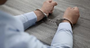mãos masculinas algemadas sobre uma mesa de madeira.